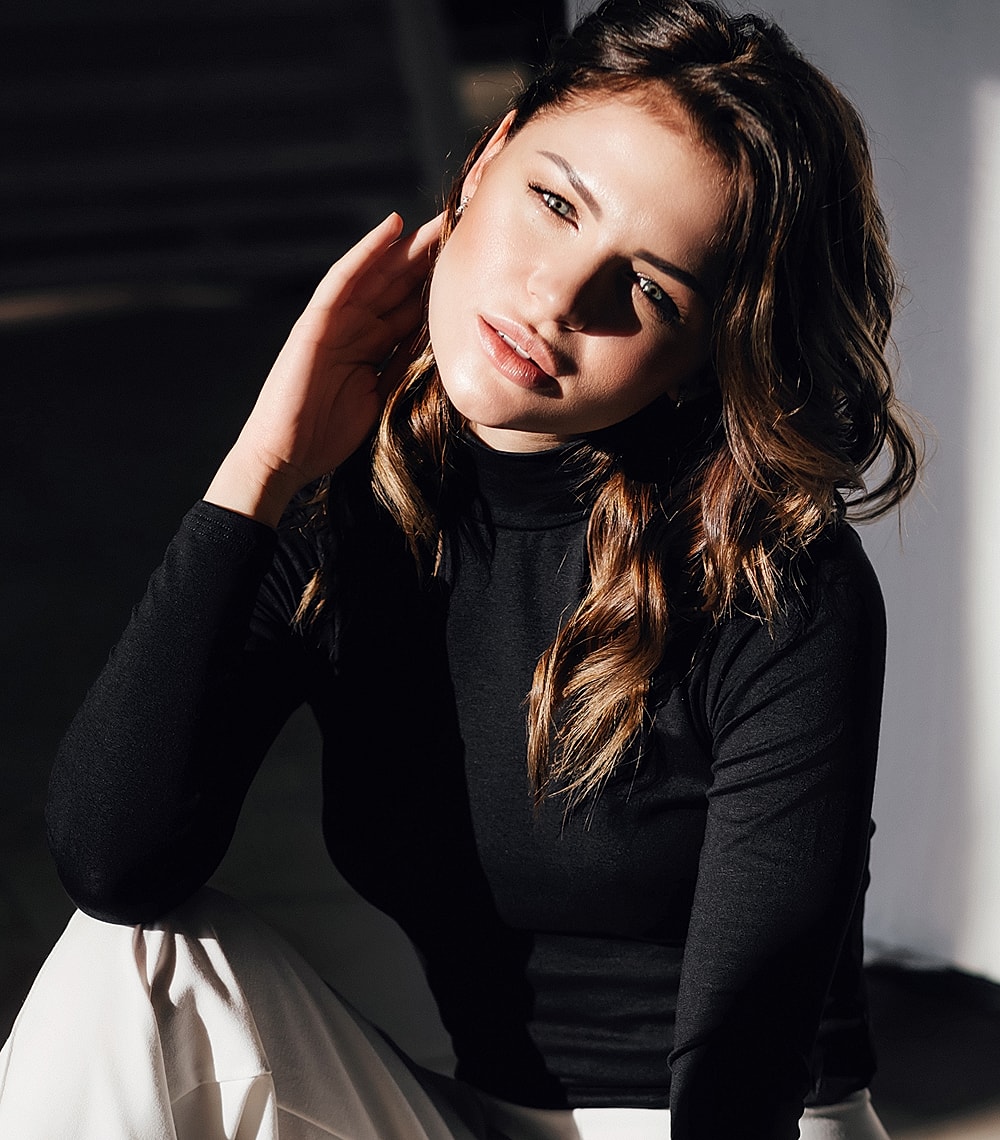 Model in a black top, soft lighting portrait.