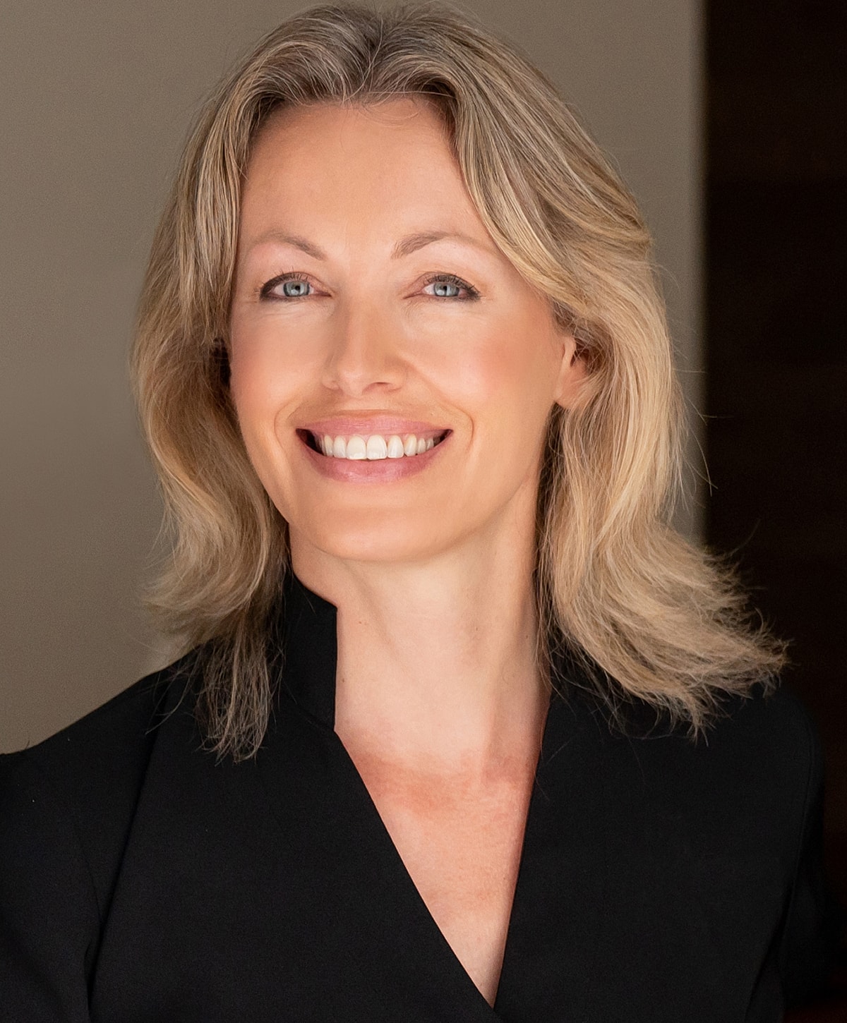 Woman smiling in professional attire, soft background.