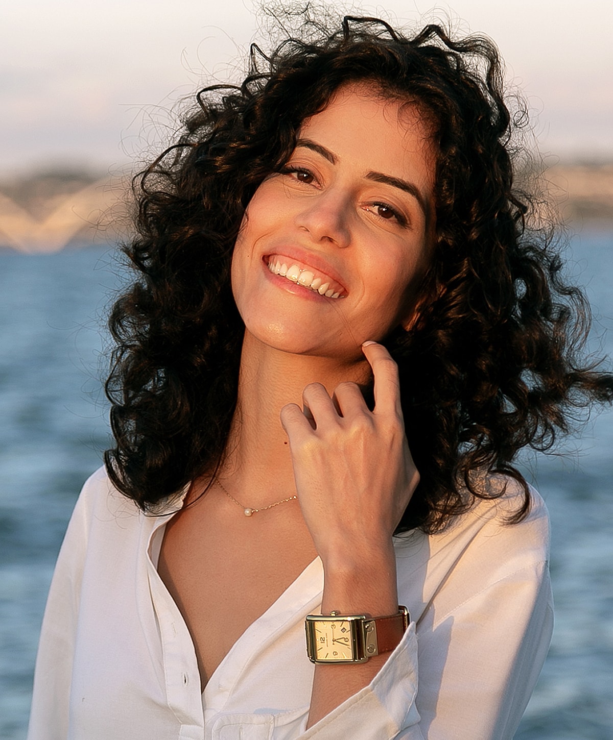 Smiling woman by the water wearing a watch.
