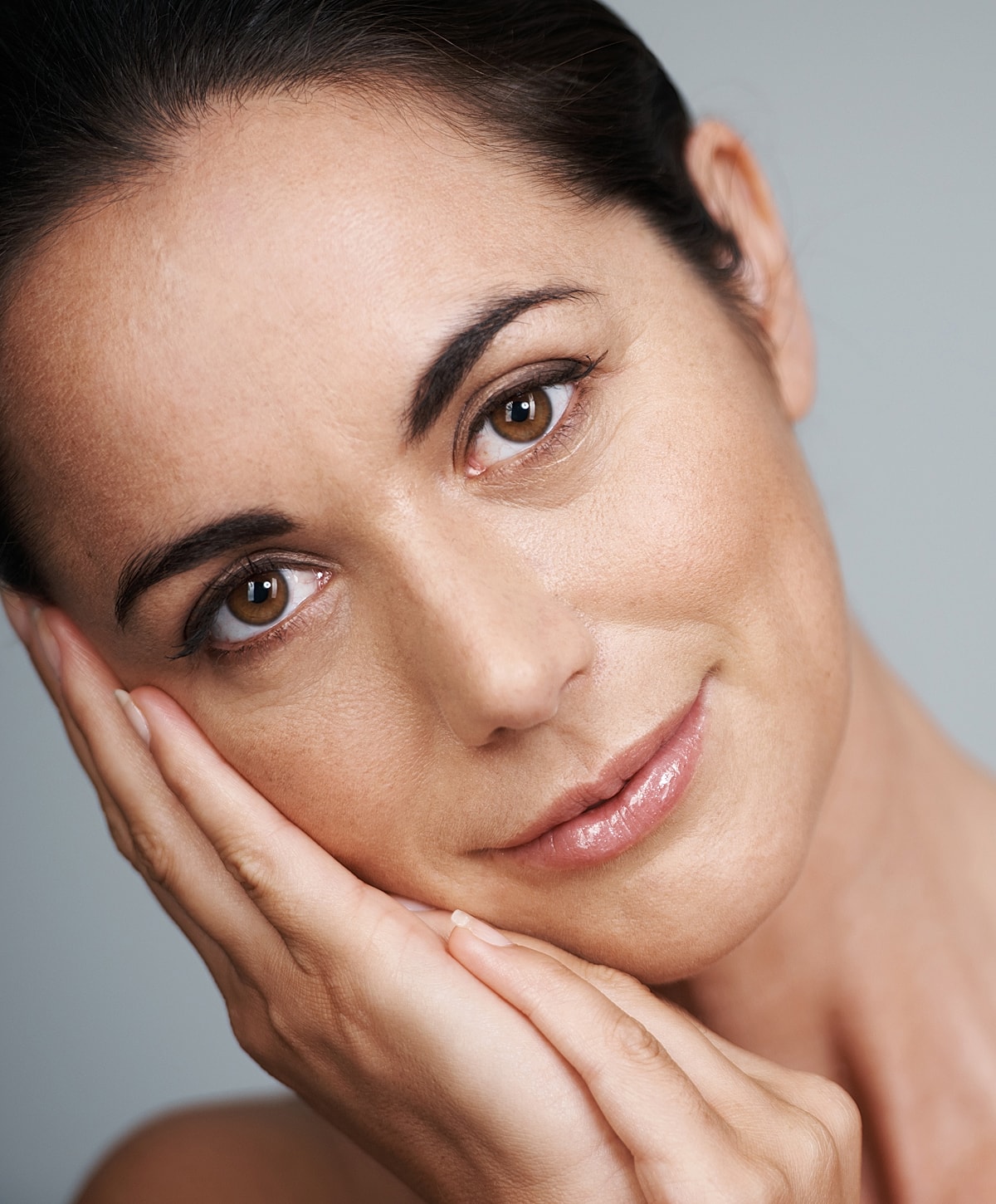 Woman resting her face on hands, smiling gently.