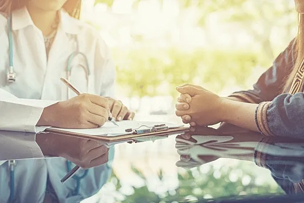Doctor consulting with patient at a desk.