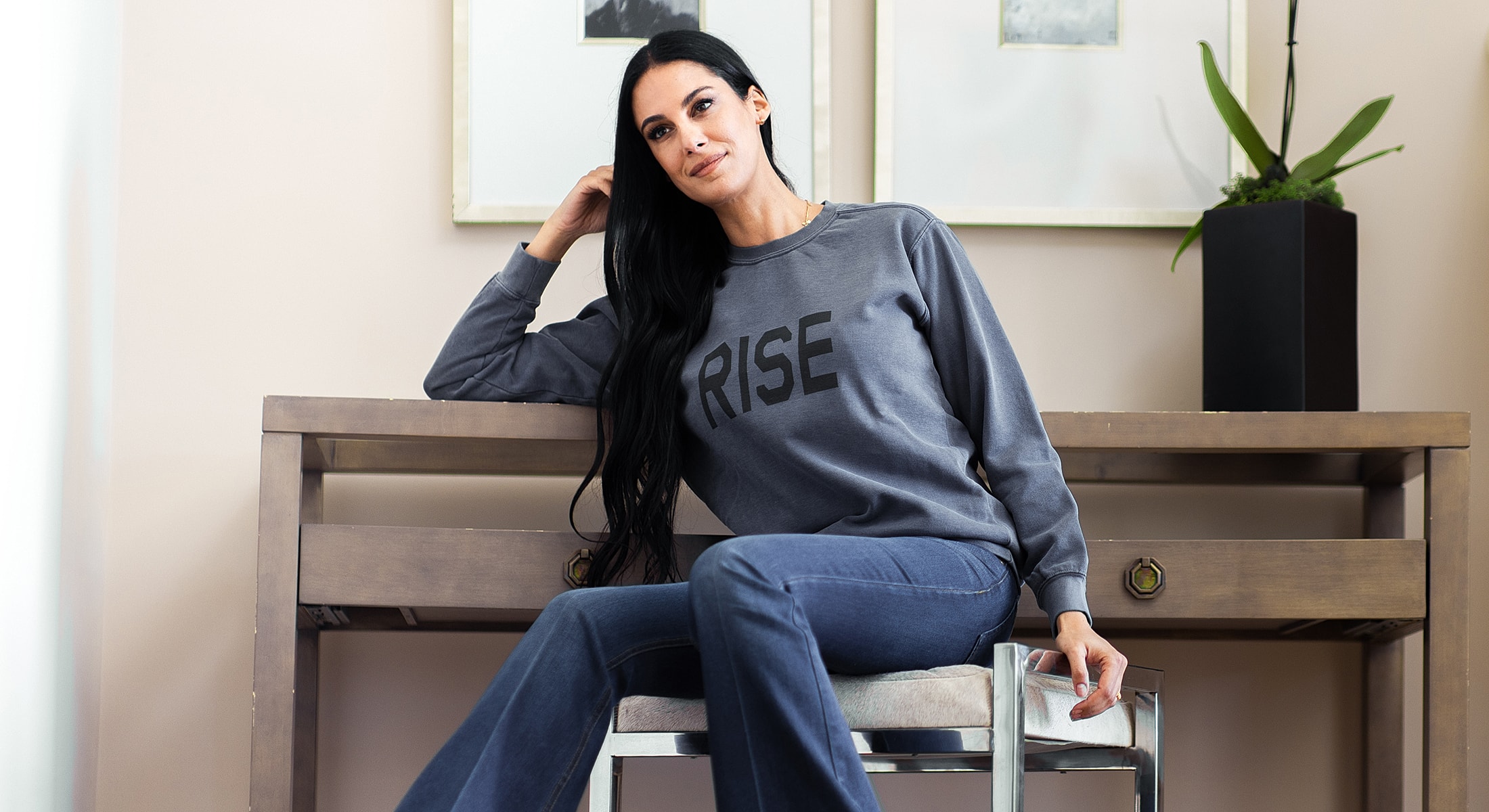 Woman in casual outfit sitting by a table.