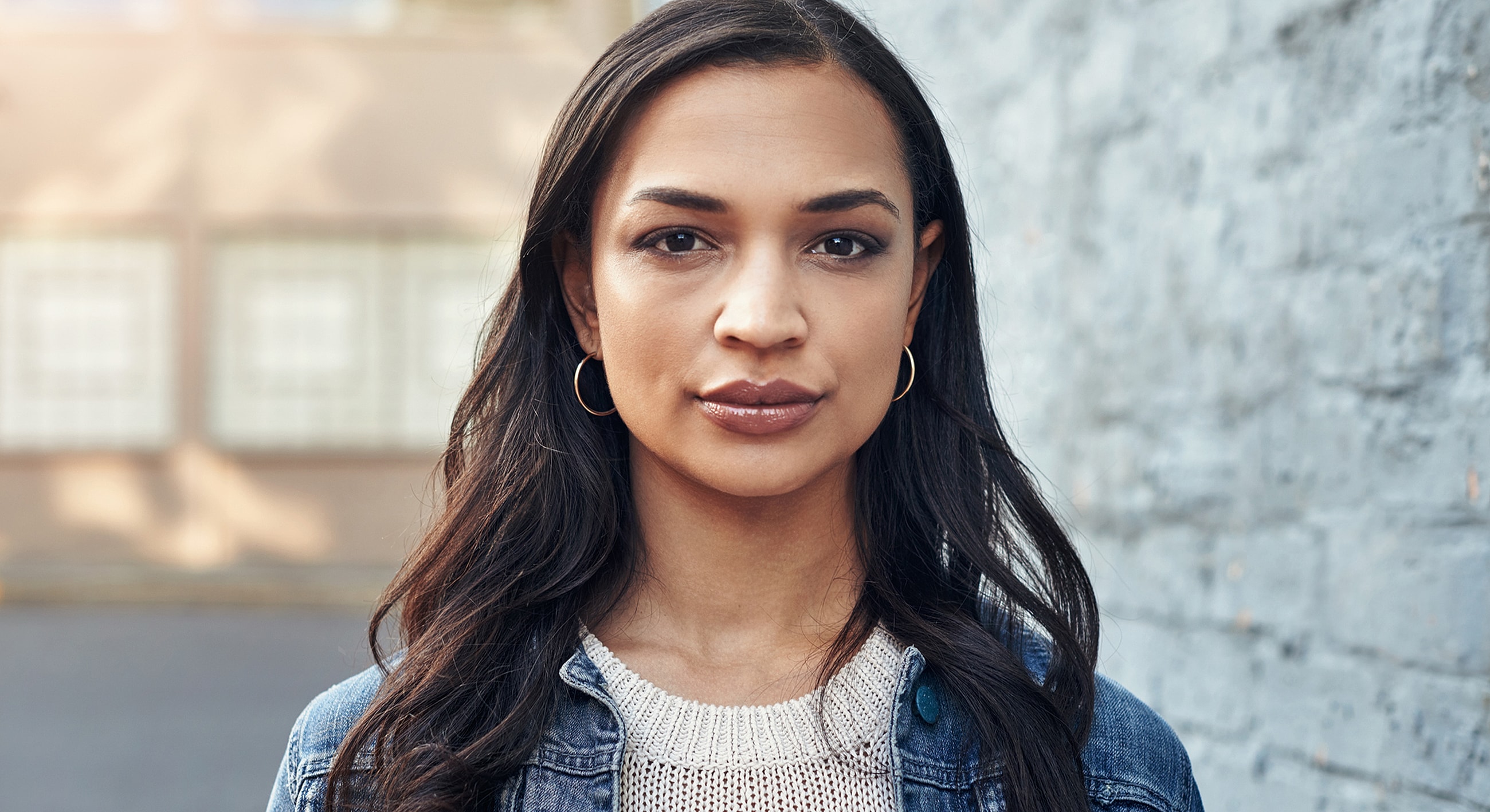 Woman with long hair against a gray wall.