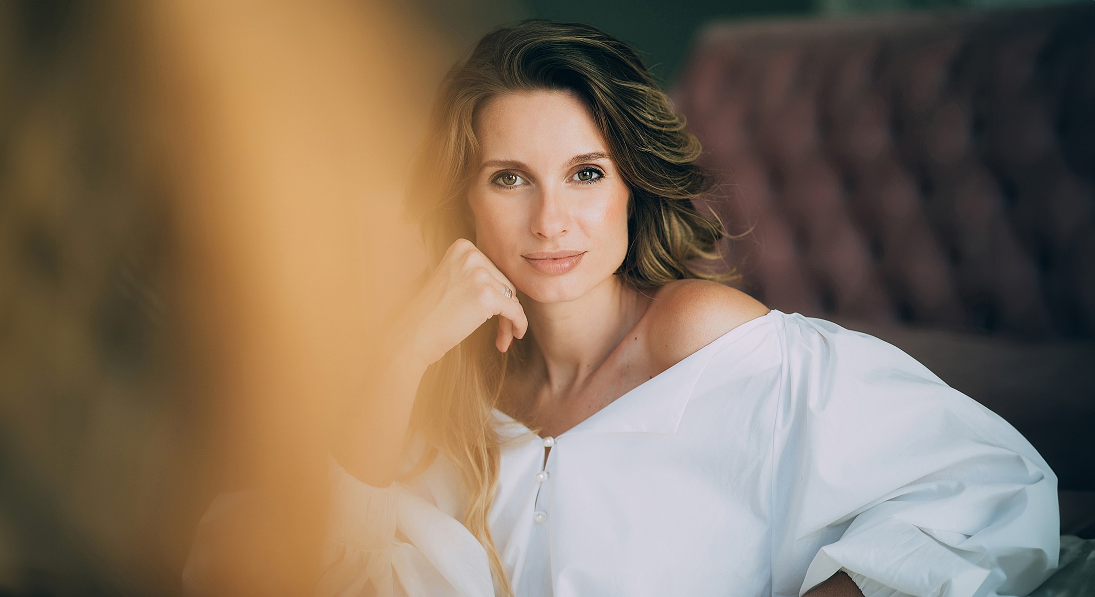 Woman in white blouse, softly smiling.